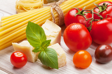 Pasta, tomatoes, basil on wooden table