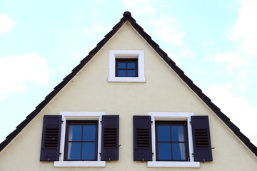 Hausgiebel mit drei Fenstern, zwei mit braunen Fensterläden