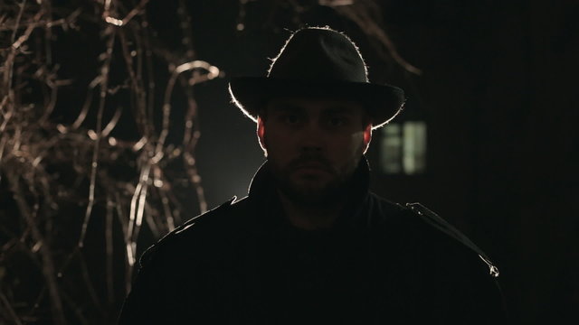 Portrait of terrible robber at night in hat and coat
