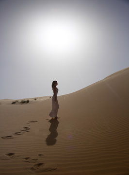 Beautiful and slim woman walks in the desert