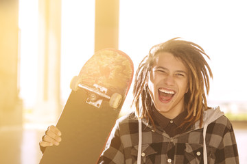 lifestyle concept of young guy  with skateboard and rasta hair w