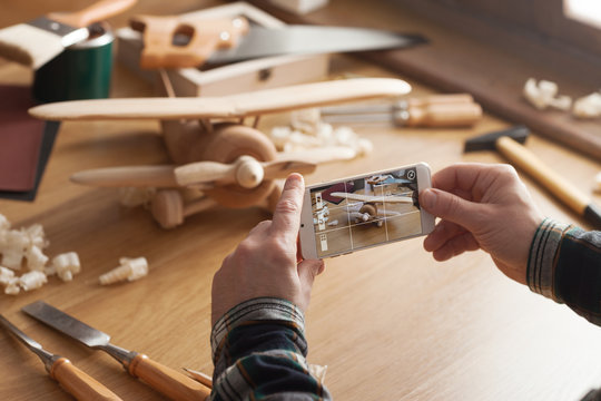 Man photographing his handmade wooden toy