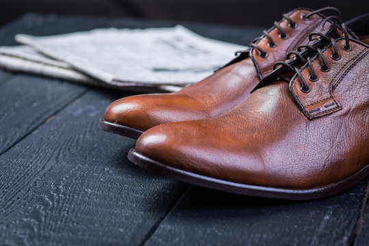 Brown leather shoes on black floor