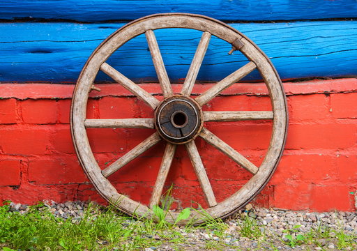 wooden wheel of old wagon on background of  timbered wall