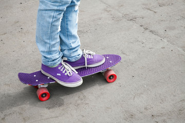 Fototapeta premium Riding skateboarder feet in blue jeans and gumshoes