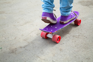 Riding skateboarder feet in jeans and gumshoes