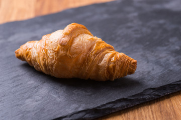 Tasty french croissant on a black stone plate