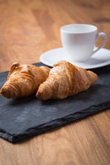 Two tasty french croissants with a cup of coffee