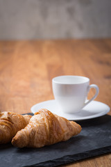 Two tasty french croissants with a cup of coffee
