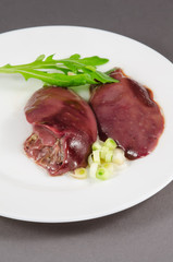 Raw chicken liver with vegetables at white plate