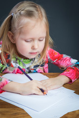 Small young girl drawing pictures with pencils