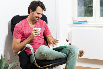 Man Sitting on Chair with Book and a Drink