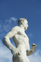 Fototapeta na wymiar Runner Athlete Old Marble Statue Blue Sky