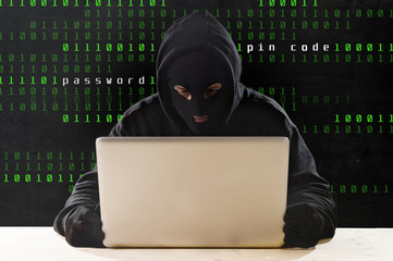 hacker in hood mask with laptop hacking system in cyber crime