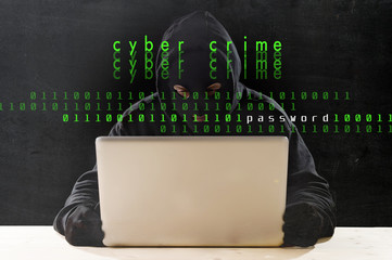 hacker in hood mask with computer hacking system in cyber crime