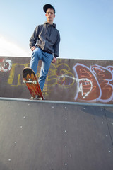 Young man with a skateboard standing on top of the skate ramp