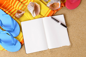 Notebook diary journal or note pad on a sunny beach sand background with seashells and accessories...