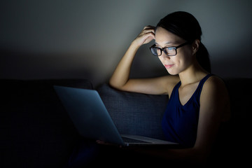 Woman lying with her laptop in night in the living room
