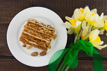 Cake slice with nut on plate. Bouquet of flower