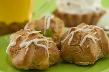 Eclair on green plate with tea, selective focus.