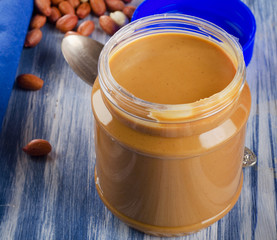 Peanut butter in a jar on blue background.