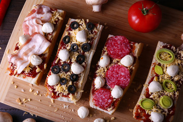 Different sandwiches with vegetables and cheese on cutting board on table close up