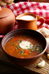 Ukrainian beetroot soup - borscht in bowl and pot, on napkin, on wooden background