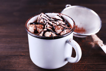 Mug of cocoa with marshmallows on wooden background