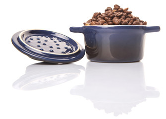 Roasted coffee beans in a blue ceramic pot over white background