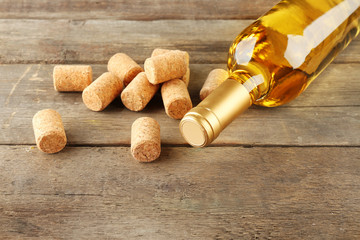 Glass bottle of wine with corks on wooden table background