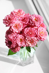 Bouquet of beautiful fresh roses on windowsill background