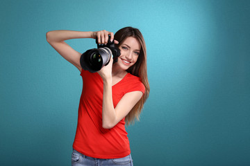 Young female photographer taking photos on blue background