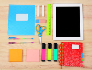 Digital tablet with stationery on wooden background