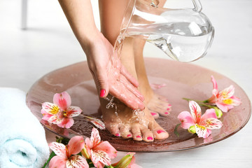 Obraz na płótnie Canvas Woman washing beautiful legs in bowl, on light background. Spa procedure concept
