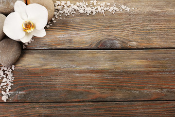 Spa stones and orchid flower on wooden background