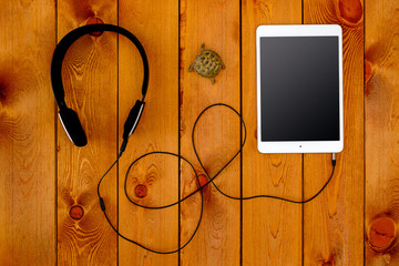 Concept with tablet and black headphones on wooden background
