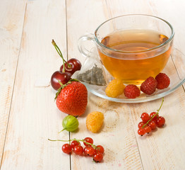 various berries and a cup of tea on a wooden table closeup