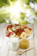 plates with cookies, cup with milk and honey on the table