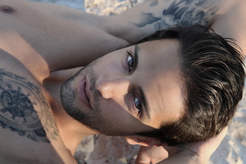 portrait of a handsome man lying on the beach