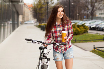 Young beautiful woman with coffee cup and a bicycle