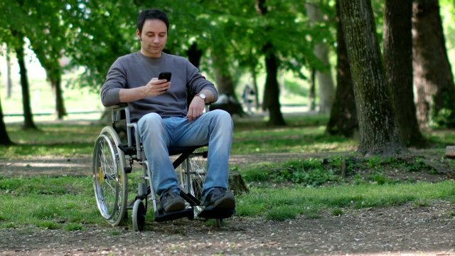 Portrait of a disabled man using his smartphone in a park