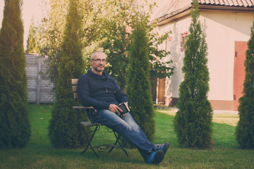 Senior man reading novel in country home garden