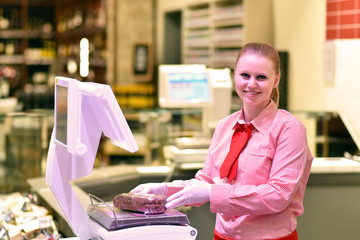 junge Verkäuferin an der Fleischtheke im Supermarkt