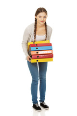 Teen woman holding heavy binders.