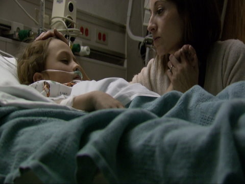 Mother comforting child in hospital bed