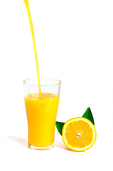orange juice pouring into glass with orange slice and leaf, isol