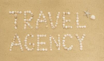 Words TRAVEL AGENCY written in sand