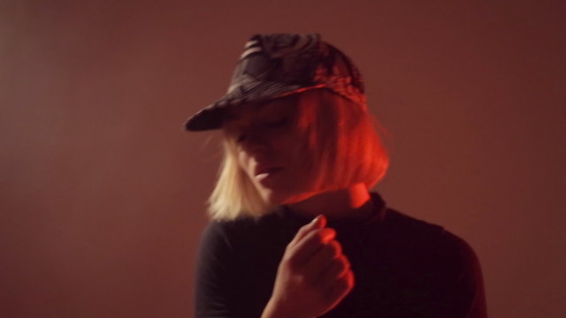 Girl in a cap moving in the studio in the smoke
