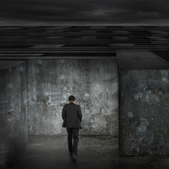 Businessman walking enter dark huge maze with cloudy sky