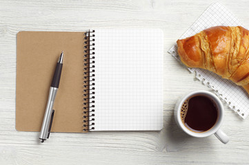 Notepad, pen, coffee and croissant